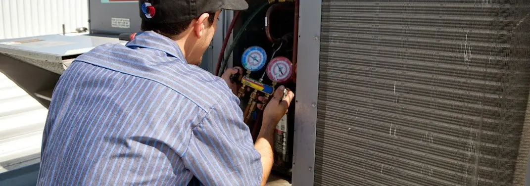 HVAC technician servicing a condenser unit in Cabot